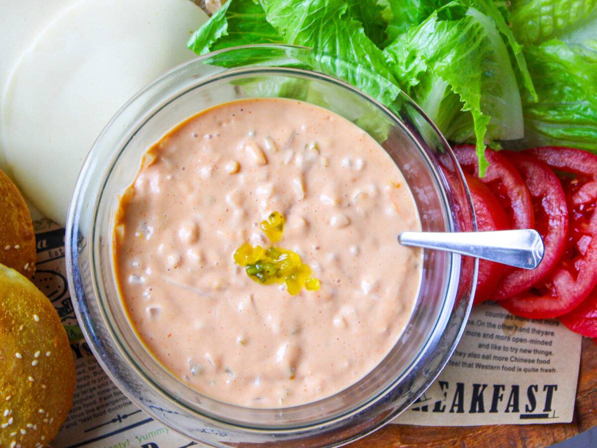 Creamy homemade burger sauce in a glass bowl made with mayonnaise, ketchup, Dijon mustard, sweet relish, sriracha, and fresh onion, surrounded by crisp lettuce, sliced tomatoes, and soft homemade burger buns. Perfect as a sauce for burgers, sandwiches, wraps, and fries.